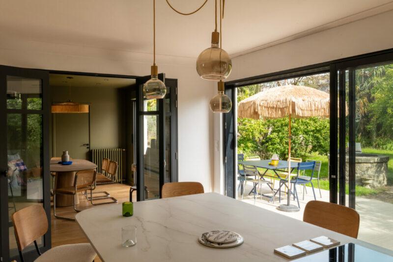 une cuisine bois et bleue, ouverte avec un ilot central  et un meuble tele qui fait la jonction une renovation sur mesure milimetrée 